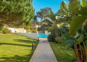 a garden with a walkway in a yard at Praia Del Rei Beach 3 Pools in Amoreira
