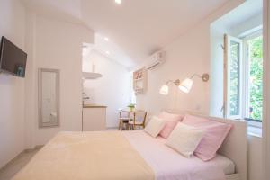1 dormitorio blanco con 1 cama grande con almohadas rosas en Apartment in Vis historic center - Mikula, Ljubica, Toma, en Vis
