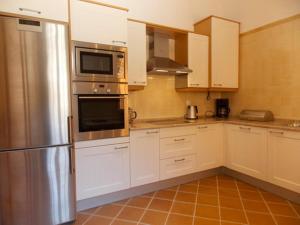 a kitchen with white cabinets and a stainless steel refrigerator at Praia Del Rei Beach 3 Pools in Amoreira
