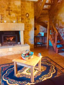 een woonkamer met een tafel en een open haard bij Maison de Montfort in Vitrac