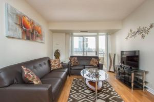 a living room with a leather couch and a tv at Platinum Suites Furnished Executive Suites in Mississauga