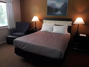 a hotel room with a large bed and a chair at Monroe Motel in Monroe