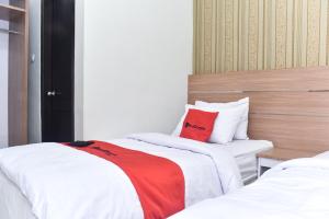 2 camas en una habitación de hotel con almohadas rojas en RedDoorz Plus near Malang Town Square, en Malang