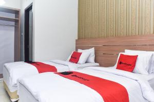 3 łóżka w pokoju z czerwonymi poduszkami w obiekcie RedDoorz Plus near Malang Town Square w mieście Malang