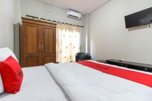a bedroom with a bed with a red pillow and a television at RedDoorz near Solo Balapan Station 2 in Solo