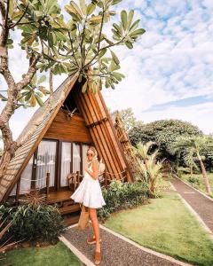 a woman in a white dress standing in front of a cabin at Batan Sabo Cottage in Nusa Penida
