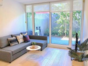 een woonkamer met een bank en een groot raam bij BPM Brighton APT with Garden LG2 in Melbourne