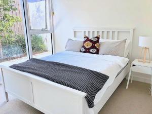a white bed in a room with a window at BPM Brighton APT with Garden LG2 in Melbourne