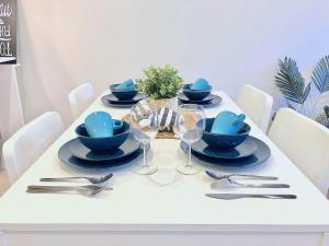 a white table with blue dishes and silverware on it at BPM Brighton APT with Garden LG2 in Melbourne