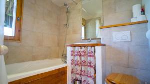 a bathroom with a tub and a shower with a shower curtain at Les Clochettes in Megève +58 photos