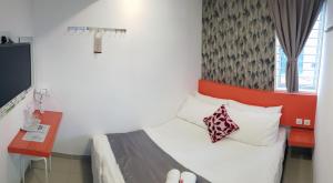 a bedroom with a bed with a red headboard and a desk at Tas 96 Inn in Kuantan