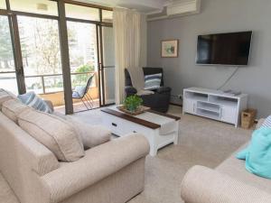 Una sala de estar con dos sofás y un televisor de pantalla plana. en Taranaki Beach House, en Port Macquarie