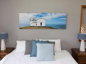 a bedroom with a white bed and a lighthouse on the ocean at Taranaki Beach House in Port Macquarie