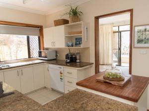 a kitchen with white cabinets and a counter top at Taranaki Beach House in Port Macquarie