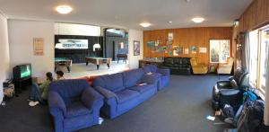 a living room with blue couches and a tv at Adventure Inn Marahau in Marahau