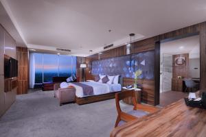 a bedroom with a bed and a living room at ASTON Madiun Hotel & Conference Center in Madiun