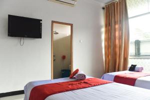 a bedroom with two beds and a flat screen tv at RedDoorz near Sultan Hasanuddin Airport 2 in Makassar