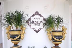 a sign on a wall with two plants in vases at Museum Hotel in George Town