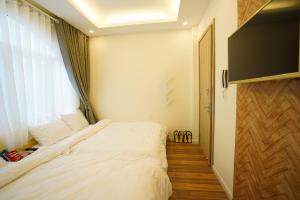 a bedroom with a white bed and a window at Homeland Hotel in Da Lat
