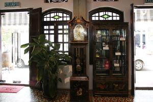 a grandfather clock in a room with a plant at Museum Hotel in George Town