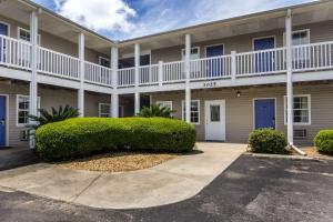 un gran edificio de apartamentos con arbustos delante de él en Motel 6-Gulf Shores, AL en Gulf Shores