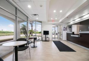 an office lobby with tables and chairs and windows at Studio 6-Ingleside, TX in Ingleside