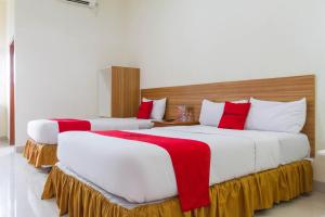 two beds in a hotel room with red and white at RedDoorz Plus @ Surapati 2 in Bandung +22 photos