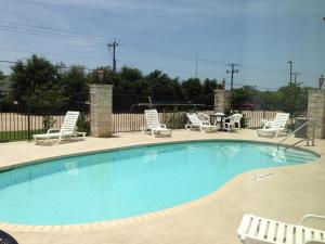 a large swimming pool with chairs and a table at Wingate by Wyndham College Station TX in College Station