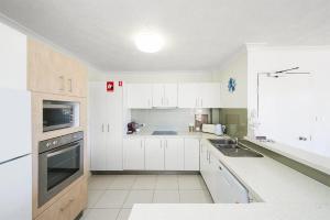 a white kitchen with white cabinets and a sink at Seabreeze 4 on Lawson Street in Byron Bay