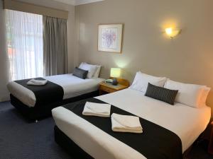 a hotel room with two beds and a window at Heritage Motor Inn Goulburn in Goulburn