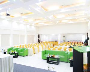 a room with green and yellow chairs and tables at Emerald Hotel in Ternate