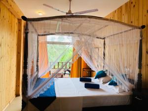 a bedroom with a canopy bed with a window at Ocean Reach Holidays in Mirissa