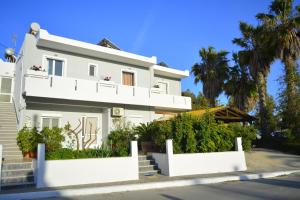 a white house with white fences and palm trees at Appartment Anna in Mastihari