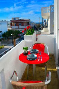 una mesa roja y una silla en un balcón con vistas al agua en Appartment Anna, en Mastichari