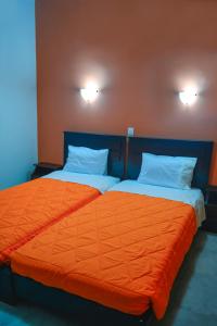 2 camas en una habitación con sábanas y almohadas de color naranja en Appartment Anna, en Mastichari