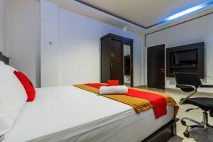 a bedroom with a large white bed with a chair at RedDoorz Premium @ Ampera Raya 2 in Jakarta +20 photos