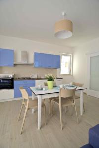 een keuken met een tafel, stoelen en blauwe kasten bij Altomare Case Vacanza in Porto Cesareo