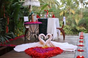 a table with two hearts and flowers on a deck at Ubud Green Resort Villas Powered by Archipelago in Ubud