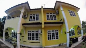 a yellow and white house with white columns at Homestay Petrajaya Kuching in Kuching