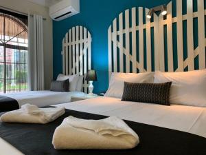 two beds in a bedroom with blue walls at Heritage Motor Inn Goulburn in Goulburn