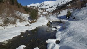 un río con nieve a un lado de una montaña en Refugi del Fornet en Alós d'Isil