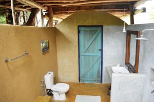 a bathroom with a toilet and a blue door at Back of Beyond - Wild Haven in Sigiriya