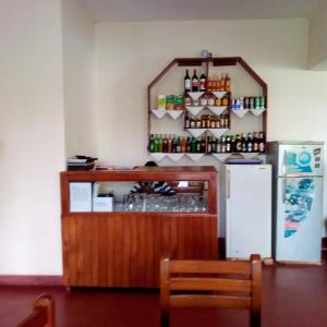 a restaurant with a refrigerator and a counter with drinks at Skyway Hotel in Entebbe