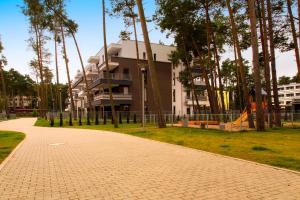 a brick path in front of a building with trees at Apartament Antoni Pogorzelica in Pogorzelica
