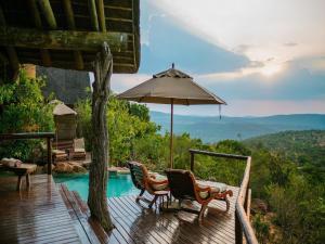 a deck with chairs and an umbrella next to a pool at Nedile Lodge in Welgevonden Game Reserve