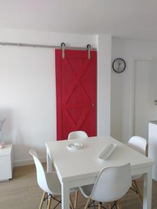 una mesa blanca con sillas blancas y una puerta roja en Apartamento ENSUEñO en Cullera playa San Antonio en Cullera