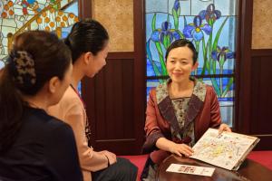 three women sitting around a table with a woman holding a map at Kanazawa Hakuchoro Hotel Sanraku -Natural Hot Spring- in Kanazawa