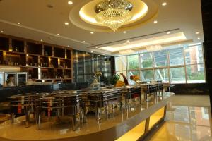 un restaurante con un bar con taburetes y una lámpara de araña en Shenzhen Baoan PLUS Gems Cube Hotel, en Bao'an
