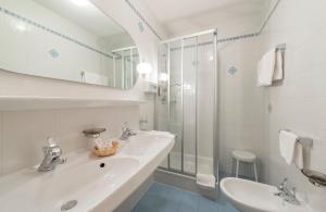 biała łazienka z umywalką i prysznicem w obiekcie Kristallhotel Corona-Krone w mieście San Vigilio di Marebbe