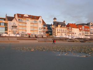 a person walking on the beach with buildings in the background at les pieds dans l'eau in Wimereux